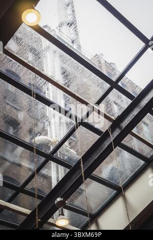 Giorno di pioggia sotto il tetto di vetro di un edificio nella città di New York Foto Stock