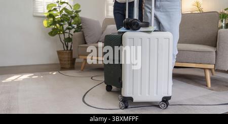 Un viaggiatore con valigie pronte per un viaggio, in piedi in un accogliente soggiorno, desideroso di imbarcarsi in una nuova avventura Foto Stock