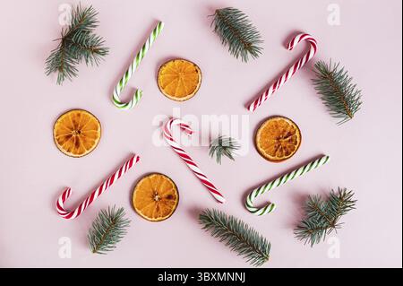 Cibo, sfondo natalizio di canne di caramelle, arance secche e rami di abete sulla vista dall'alto rosa Foto Stock