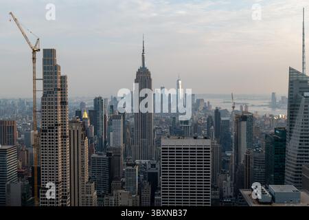 Vista aerea di un paesaggio urbano al tramonto, che mostra una miscela di iconici grattacieli e cantieri attivi sotto un cielo moodico. Foto Stock
