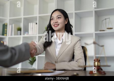 Un avvocato professionista in un ufficio moderno stringe la mano a un cliente, simboleggiando la fiducia, l'accordo e il successo della negoziazione Foto Stock