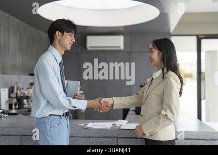 Una stretta di mano tra due professionisti in un moderno ambiente di caffetteria, che simboleggia un accordo e una partnership di successo Foto Stock