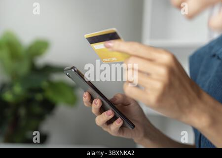 Pagamenti digitali e pianificazione finanziaria. Una giovane donna utilizza con sicurezza la sua carta di credito e lo smartphone per tenere traccia delle spese Foto Stock