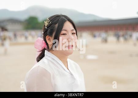 A giugno a Seul, al Palazzo Gyeongbokgung, due donne coreane sui trent'anni chiacchierano tra la folla che indossava un grazioso hanbok rosa e blu cielo, i loro sorrisi sono ripresi Foto Stock