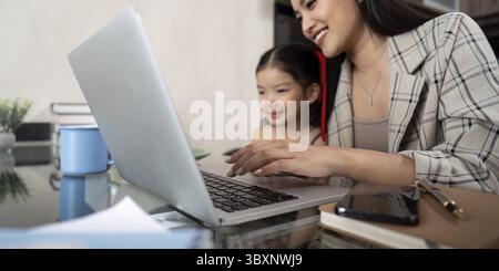 Mamma che lavora lavora da casa. Donna d'affari e bambino carino che utilizza un notebook lavora come libero professionista, lavora a casa, e in famiglia Foto Stock
