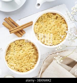 Mela sbriciolata con streusel su tavolo grigio chiaro. Colazione mattutina con fiori Foto Stock