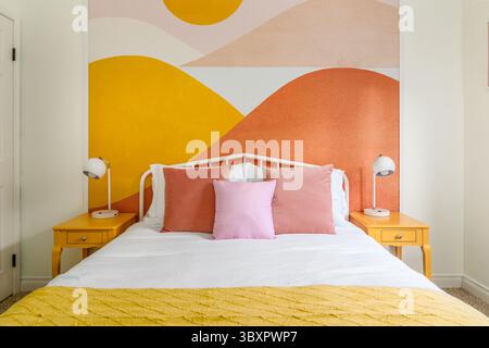 Interni colorati e moderni in stile boho chic nel deserto. Letto, tavolini laterali, lampade e murales colorati. Vista frontale. Foto Stock