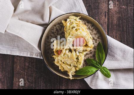 Cibo, primo piano di salsicce avvolte in pancake di cavolo tagliati su un piatto con vista dall'alto del tavolo Foto Stock