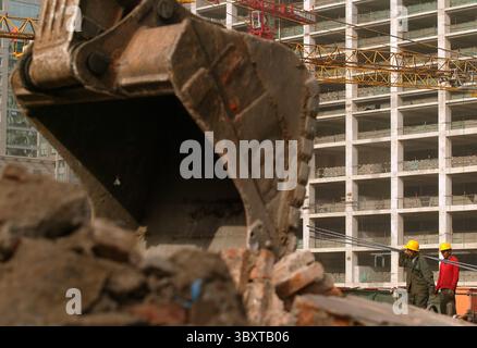 29 aprile 2007, PECHINO, CINA: I lavoratori edili trasportano barre di ferro su un cantiere mentre una gru demolisce un vecchio quartiere cinese nel centro di Pechino, Cina, il 29 aprile 2007. I funzionari stanno esaminando nuovi passi per rinfrescare l'economia sfrigolante della Cina, mentre la sua principale agenzia di pianificazione ha chiesto un credito bancario più stretto e restrizioni sulla costruzione, hanno riferito i media statali. Il rapporto ha suggerito che Pechino ritiene che le misure precedenti, tra cui un aumento del tasso di interesse ad aprile, non stiano contenendo la crescita fuorviante della spesa per le fabbriche e altre attività che i leader cinesi temono potrebbero innescare un cri finanziario Foto Stock