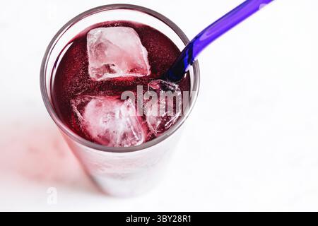 Bevanda a base di frutti di bosco rossi su sfondo bianco. Cocktail con vista dall'alto e cubetti di ghiaccio. Un'idea di rinfresco estivo. Bevanda fredda con bollicine e paglia. Foto Stock