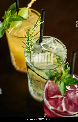 Una vivace gamma di cocktail colorati con menta e rosmarino, adornati con ghiaccio e serviti in eleganti bicchieri. aroma e freschezza perfetti Foto Stock