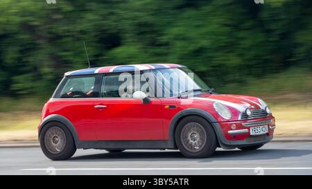 Milton Keynes,Bucks,UK - 17 luglio 2025: 2003 Mini Cooper rossa con tetto Union Jack che guida su una strada britannica Foto Stock