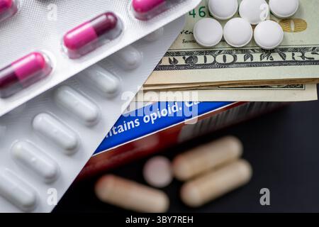 Un concetto di droga, dipendenza da oppioidi con pillole mediche e bollette del dollaro americano sopra una scatola di medicina contenente oppioidi. Foto Stock