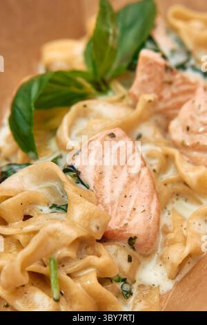 Un appetitoso piatto di pasta cremosa con morbidi filetti di salmone, basilico fresco e spinaci, il tutto avvolto in una ricca salsa all'aglio. perfetto per un buongustai Foto Stock