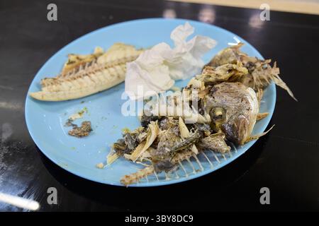 Un piatto mostra i resti del pesce dorado, con la sua pelle croccante e l'intricata struttura ossea Foto Stock