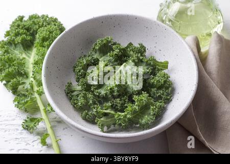 Cibo, foglie di cavolo riccio fresche tritate in un recipiente di ceramica su sfondo grigio chiaro. Cibo disintossicante sano Foto Stock