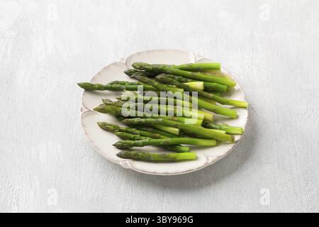 Cibo, asparagi cotti al vapore su un piatto su sfondo grigio chiaro, vista dall'alto. Dieta sana Foto Stock