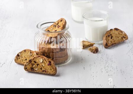 Cibo, Un vasetto di vetro di biscotti di zucca con mirtilli rossi e noci su fondo testurizzato grigio chiaro. Delizioso cibo fatto in casa Foto Stock