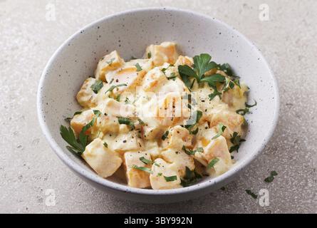 Cibo, ciotola di zucca in salsa di panna acida cosparsa di prezzemolo fresco sul tavolo in pietra beige, vista dall'alto. Cibo vegetariano Foto Stock