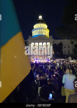 27 febbraio 2022, Sacramento, California, USA: I colori del Campidoglio della California sono stati cambiati in blu e giallo per mostrare sostegno all'Ucraina, mentre le persone si riuniscono di fronte all'edificio per protestare contro l'invasione russa dell'Ucraina. Un grande striscione giallo dice: "Dio protegga l'Ucraina". (Immagine di credito: © Andrew Silk/ZUMA Press Wire Service) Foto Stock