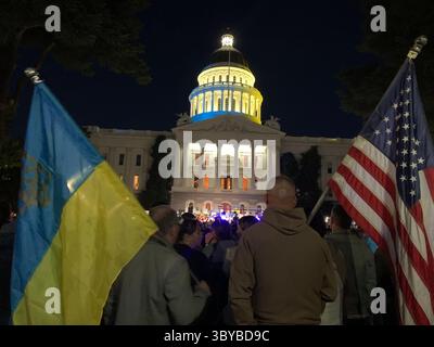 27 febbraio 2022, Sacramento, California, USA: I colori del Campidoglio della California sono stati cambiati in blu e giallo per mostrare sostegno all'Ucraina, mentre le persone si riuniscono di fronte all'edificio per protestare contro l'invasione russa dell'Ucraina. Un grande striscione giallo dice: "Dio protegga l'Ucraina". (Immagine di credito: © Andrew Silk/ZUMA Press Wire Service) Foto Stock