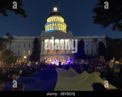 27 febbraio 2022, Sacramento, California, USA: I colori del Campidoglio della California sono stati cambiati in blu e giallo per mostrare sostegno all'Ucraina, mentre le persone si riuniscono di fronte all'edificio per protestare contro l'invasione russa dell'Ucraina. Un grande striscione giallo dice: "Dio protegga l'Ucraina". (Immagine di credito: © Andrew Silk/ZUMA Press Wire Service) Foto Stock