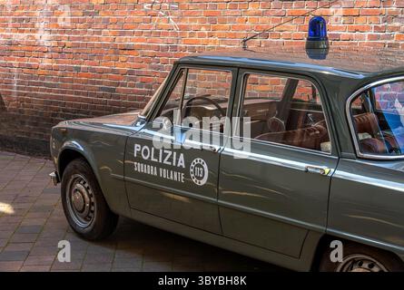 Amburgo, Germania - 30 giugno 2025: Auto della polizia italiana d'epoca parcheggiata da un muro di mattoni, dal design classico e dalla sirena blu. Foto Stock