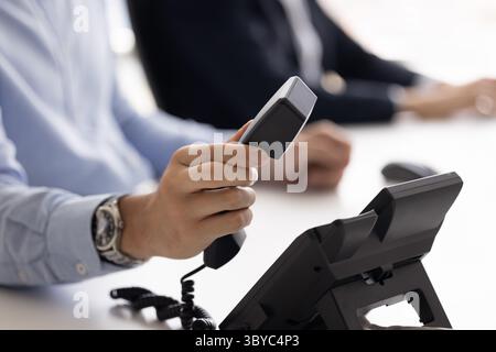 Primo piano maschio che tiene il ricevitore del telefono, risponde o termina la telefonata Foto Stock