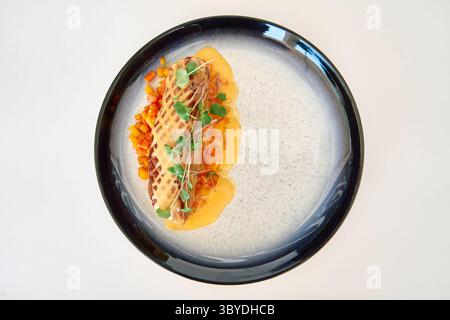 Un piatto di pesce alla griglia splendidamente presentato con verdure colorate e microgreen, disposto artisticamente su un elegante piatto in ceramica, con un per Foto Stock