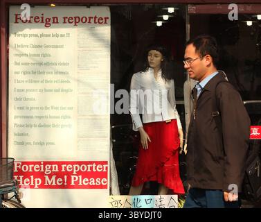 22 febbraio 2011, PECHINO, CINA: Un uomo cinese passa davanti a un negozio di abbigliamento che pubblicizza una richiesta di aiuto ai giornalisti stranieri per un aiuto contro la corruzione locale a Pechino il 22 febbraio 2011. La Cina deve trovare nuovi modi per disinnescare i disordini, ha detto questa settimana il capo della sicurezza interna del paese, sottolineando l'ansia della capitale per il controllo dopo che la polizia ha annullato le richieste di raduni ispirati alle rivolte in Medio Oriente. (Immagine di credito: © Stephen Shaver/ZUMA Press Wire) Foto Stock