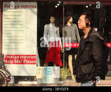 22 febbraio 2011, PECHINO, CINA: Un uomo cinese passa davanti a un negozio di abbigliamento che pubblicizza una richiesta di aiuto ai giornalisti stranieri per un aiuto contro la corruzione locale a Pechino il 22 febbraio 2011. La Cina deve trovare nuovi modi per disinnescare i disordini, ha detto questa settimana il capo della sicurezza interna del paese, sottolineando l'ansia della capitale per il controllo dopo che la polizia ha annullato le richieste di raduni ispirati alle rivolte in Medio Oriente. (Immagine di credito: © Stephen Shaver/ZUMA Press Wire) Foto Stock