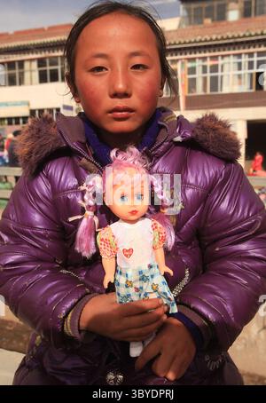 6 febbraio 2012, XIAHE, PROVINCIA DI GANSU, CINA: Una ragazza tibetana tiene la sua bambola vicino al monastero di Labrang, il più grande monastero tibetano fuori Lhasa, durante il Festival del monlam tibetano a Xiahe, una piccola città nella provincia di Gansu sull'altopiano tibetano, 5 febbraio 2012. Lunedì la Cina ha avvertito i funzionari del governo tibetano che il mancato mantenimento della stabilità potrebbe comportare la perdita di posti di lavoro o l'accusa penale, l'ultimo segno di crescenti tensioni etniche tra i tibetani e il governo cinese. (Immagine di credito: © Stephen Shaver/ZUMA Press Wire) Foto Stock