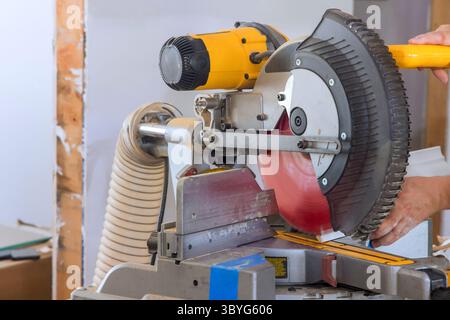 L'artigiano utilizza una sega circolare per tagliare pezzi di legno per migliorare la casa in interni ben illuminati Foto Stock