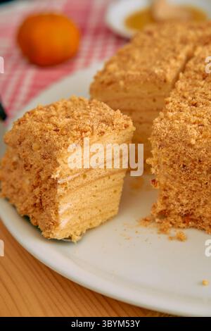 Appetitosa torta al miele ricoperta di briciole dolci, perfetta per un delizioso dessert o un dolce gourmet, servita su un piatto bianco. Foto Stock