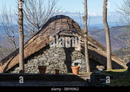 O Cebreiro, Spagna. Pallozas tradizionali in paglia nel villaggio di montagna di o Cebreiro circondato dal paesaggio della Galizia e dalle colline della Cam Foto Stock