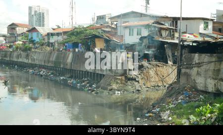 MANDAUE CITY, FILIPPINE, 15 GIUGNO 2025: Baraccopoli filippina povera gente di fiume che cucina cibo rifiuti spazzatura discarica rifiuti inquinamento fecale Foto Stock