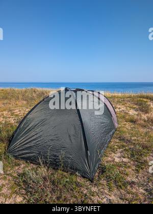 Ripresa verticale di una tenda su una spiaggia di sabbia a Nova, Estonia. Campeggio estivo, viaggi e avventura costiera appartati. Foto Stock