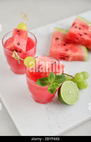 Succo di anguria fresco con menta e lime nel bicchiere su sfondo chiaro. Dolce dessert estivo, frullato, cocktail concetto di cibo sano. Ora legale. Foto Stock