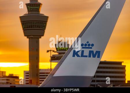 AMSTERDAM, PAESI BASSI, 3 LUGLIO 2025, ala aeroplano con aletta che mostra il logo della compagnia aerea KLM con torre di controllo dell'aeroporto sullo sfondo del tramonto Foto Stock