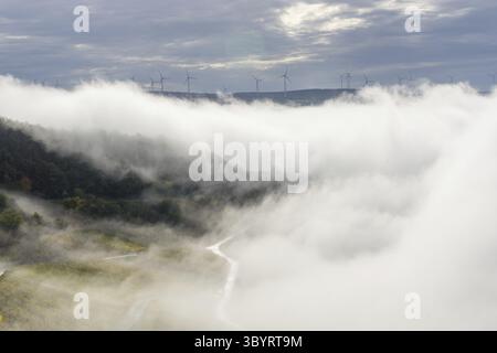 Condizioni meteorologiche di inversione nella valle vicino al Vlliage tedesco chiamato Bernkastell-Kues. Con la centrale eolica in background Foto Stock