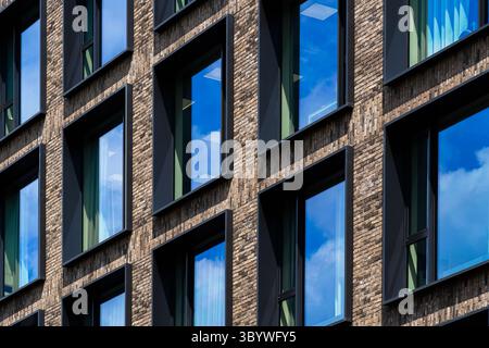 Moderna facciata residenziale in mattoni con finestre riflettenti profonde e simmetria pulita Foto Stock