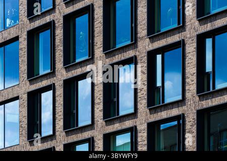 Moderna facciata residenziale in mattoni con finestre riflettenti profonde e simmetria pulita Foto Stock