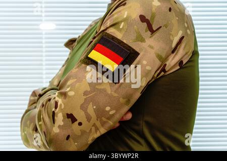 Uomo in abiti militari con bandiera tedesca sulla manica. Simbolo del servizio nazionale Foto Stock