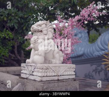 statua del leone di fronte all'albero dei ciliegi in fiore Foto Stock