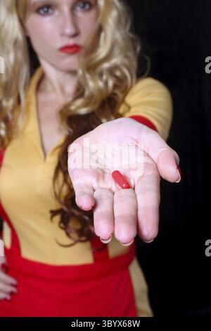 Cameriera con Red Nail Polish Holding Red pill Foto Stock