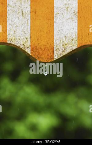 Pioggia. Tenda su un balcone e gocce d'acqua su uno sfondo naturale colorato durante una giornata di primavera Foto Stock