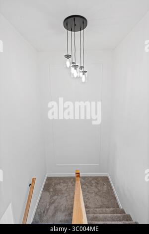 Scala con lampada appesa al soffitto. L'apparecchio di illuminazione è composto da diverse lampadine ed è appeso al soffitto Foto Stock