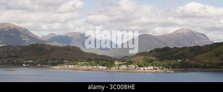 Una vista panoramica dalla Costa Nord 500 del villaggio illuminato dal sole di Shieldaig, con le montagne di Beinn Alligin e Liathach in lontananza Foto Stock