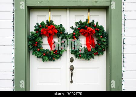 Ghirlande verdi con nastri rossi e baule appese alla porta Foto Stock