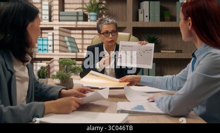Leader del team caucasico che mostra grafici di puntamento colleghi di lavoro attività di analisi aziendale discutere statistiche diverse donne imprenditrici Foto Stock